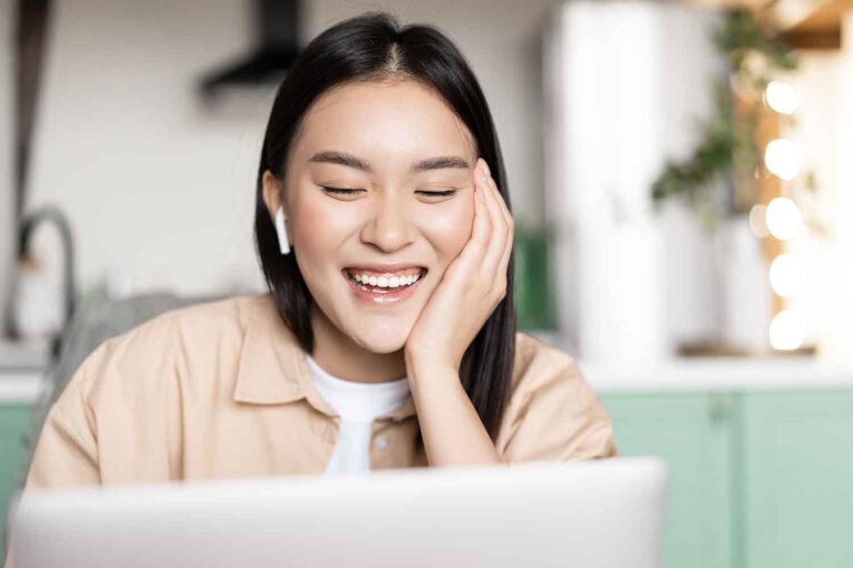 portrait-happy-asian-girl-talks-video-chat-communicating-with-laptop-application-laughing